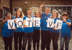 Vision Foundation staff in blue t-shirts holding up letters spelling VOTE VF