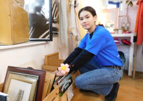 A young lady working as a volunteer in charity shop wearing Vision Foundation blue t-shirt