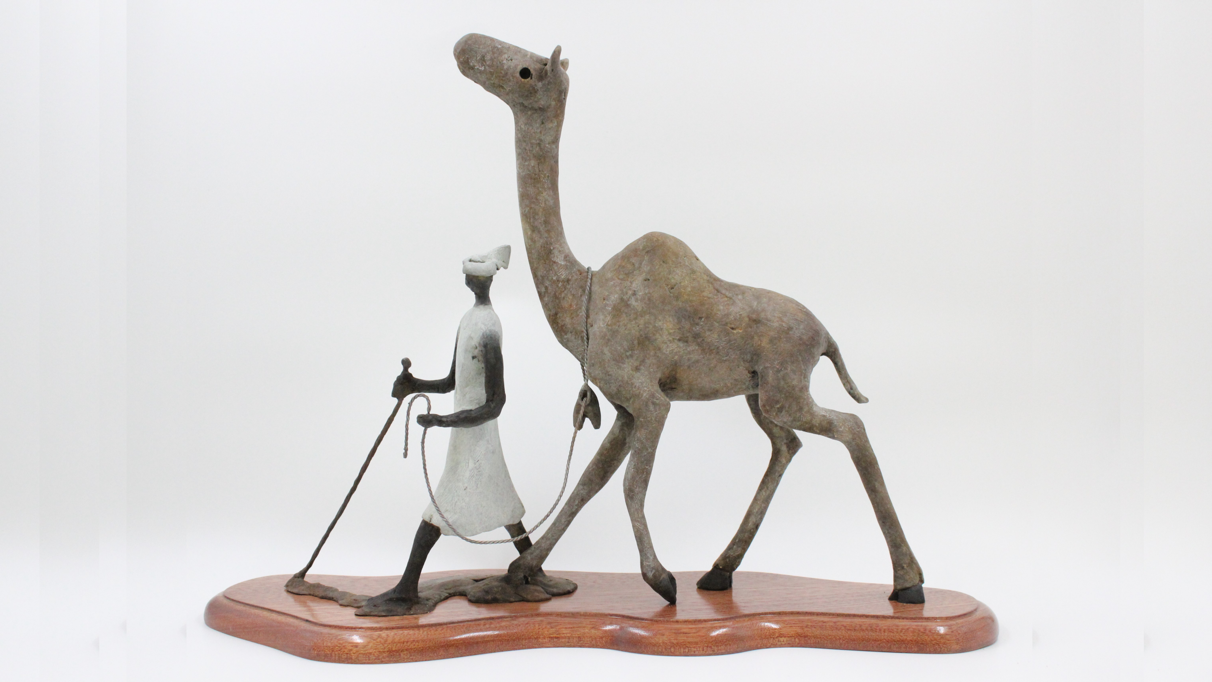 Terry Mathews’ carefully crafted bronze sculpture, depicting a herder in a white garment leading a camel.