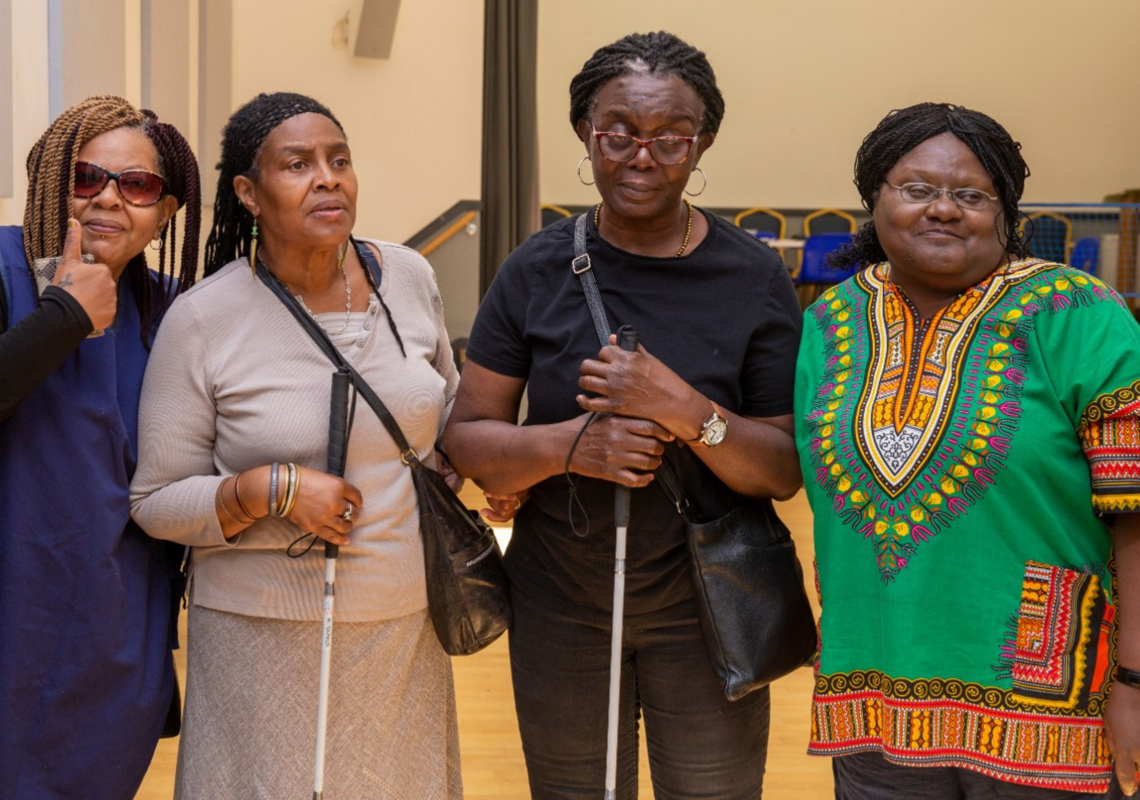 Four women from Croydon Vision line up in a row, two of whom are holding white canes