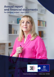 Front cover of Vision Foundation annual report. Image shows a white woman with long blonde hair in a pink shirt, holding a white cane, standing in front of a bookshelf.
